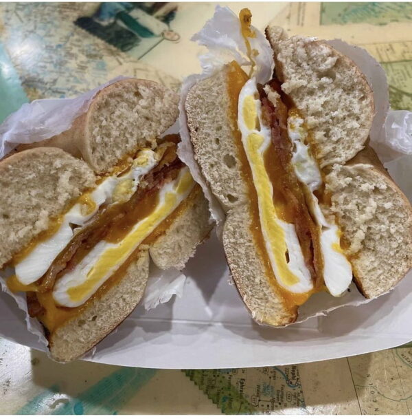 A pair of toasted bagel sandwiches made with melted cheese and fried eggs