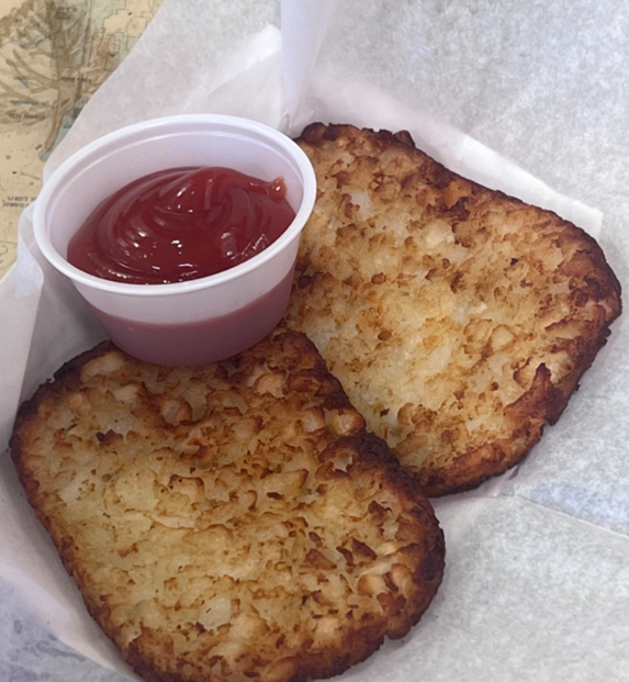 A pair of hash brown with some tomato sauce.